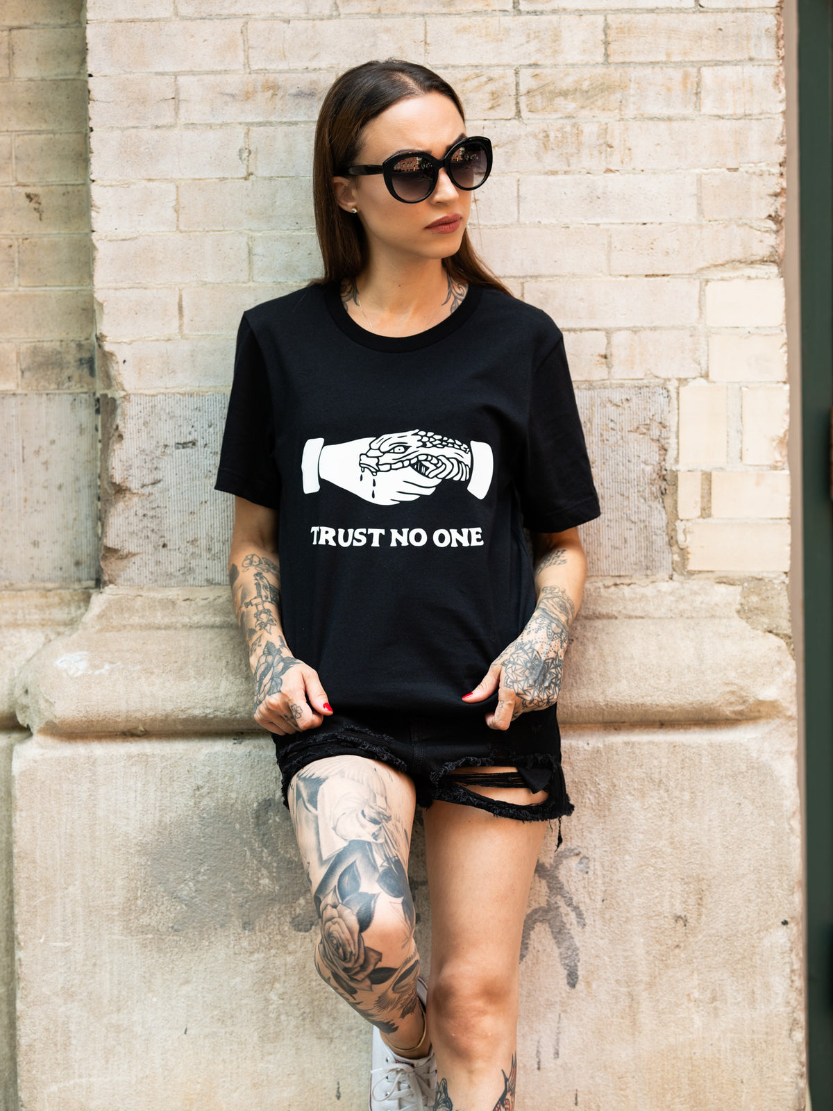 Janice Danger wearing a unisex black t-shirt that reads &quot;trust no one&quot; with denim shorts