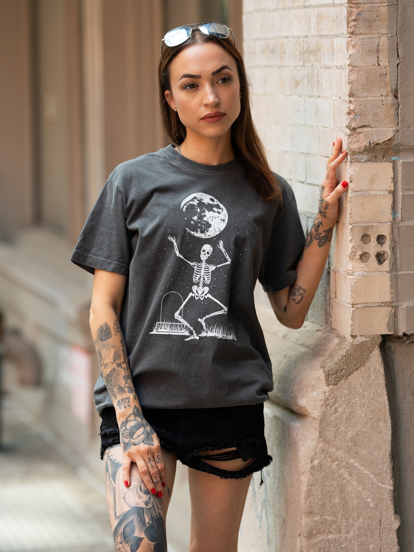 Janice Danger wearing a unisex, charcoal t shirt with a dancing skeleton grpahic in white