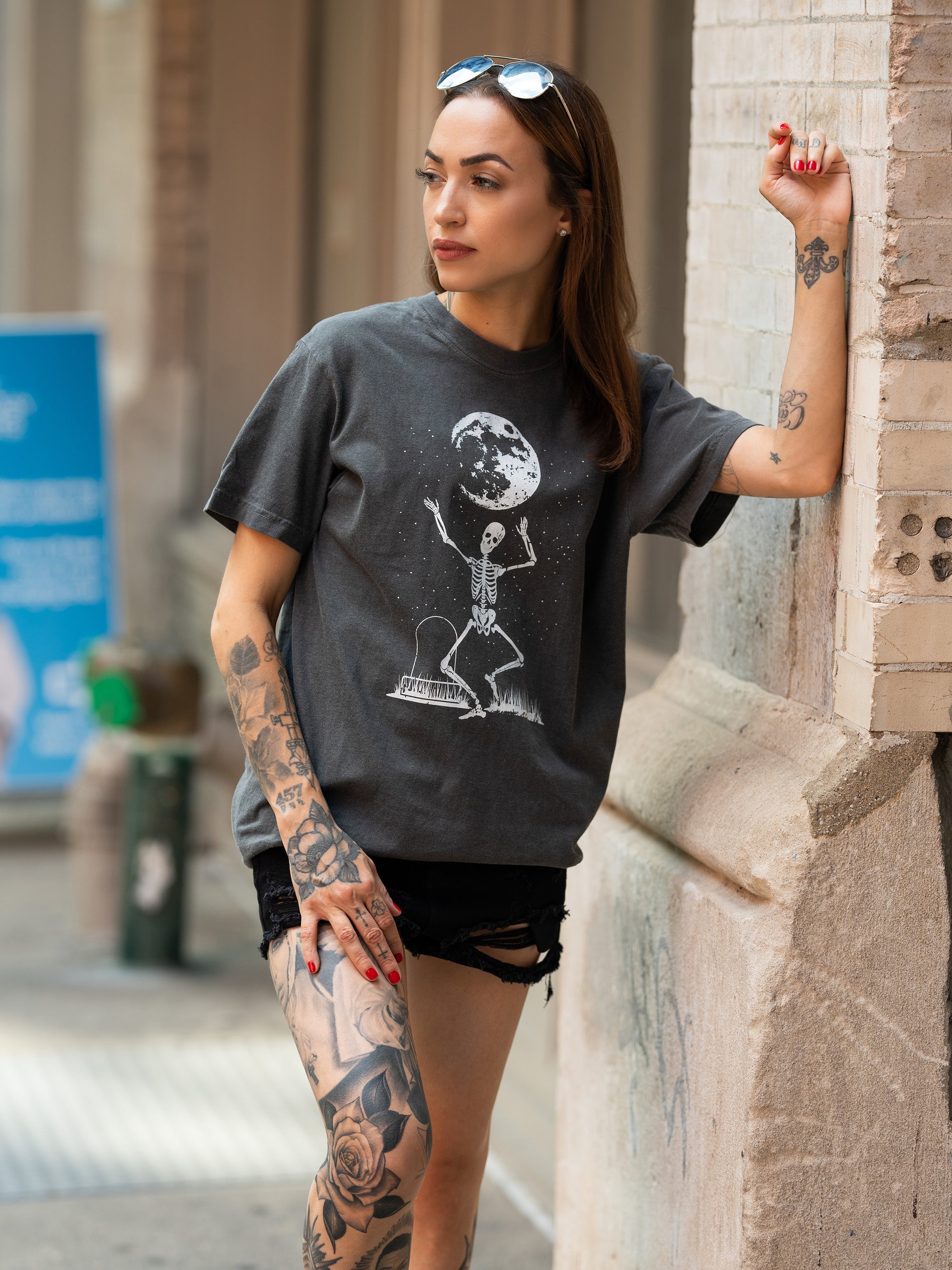 Janice Danger wearing a unisex, charcoal t shirt with a dancing skeleton grpahic in white