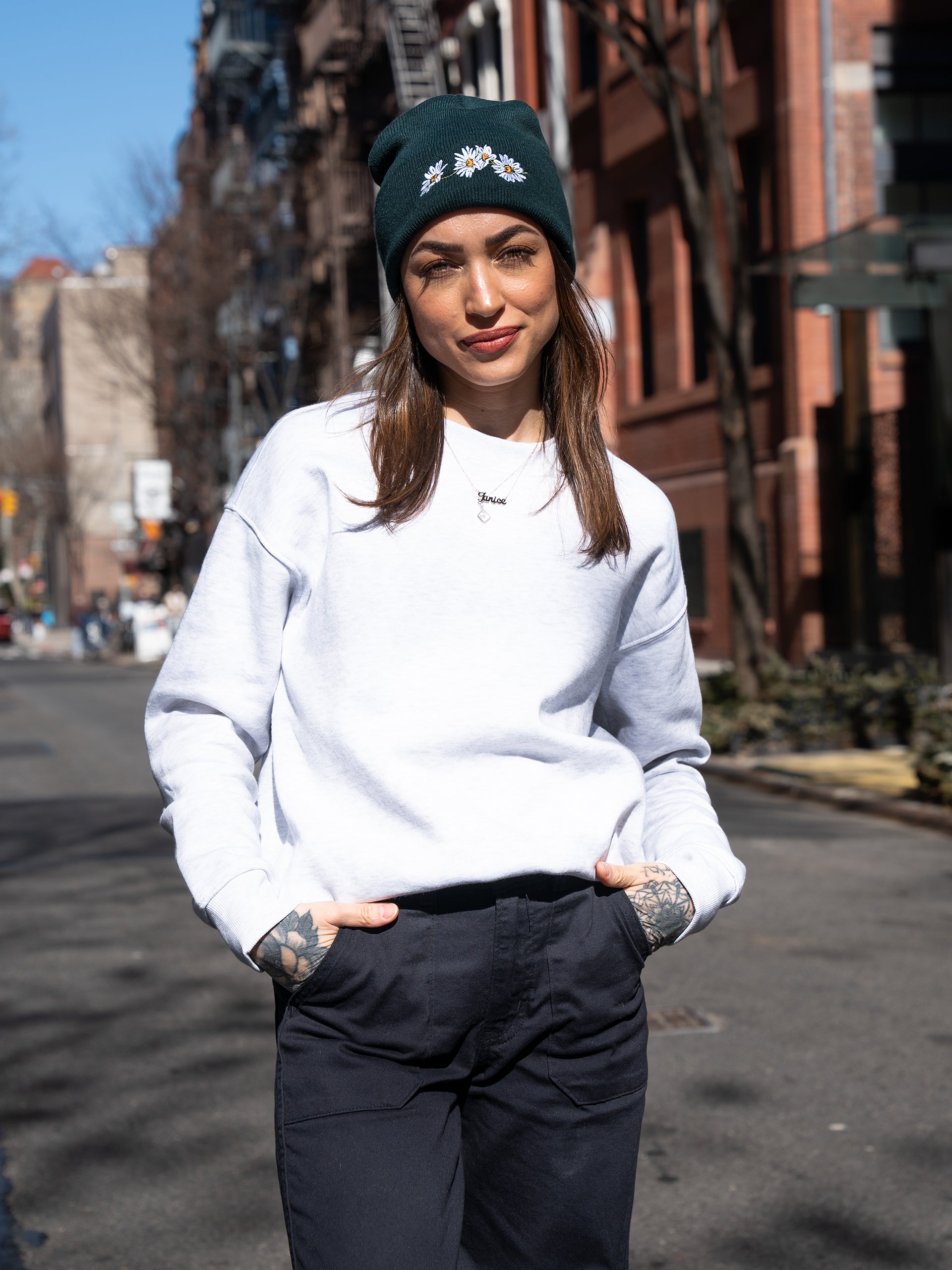 Janice Danger wearing the Nostalgic Daisy pine green beanie with white daisy embroidery. Photographed on Sullivan Street NYC. 