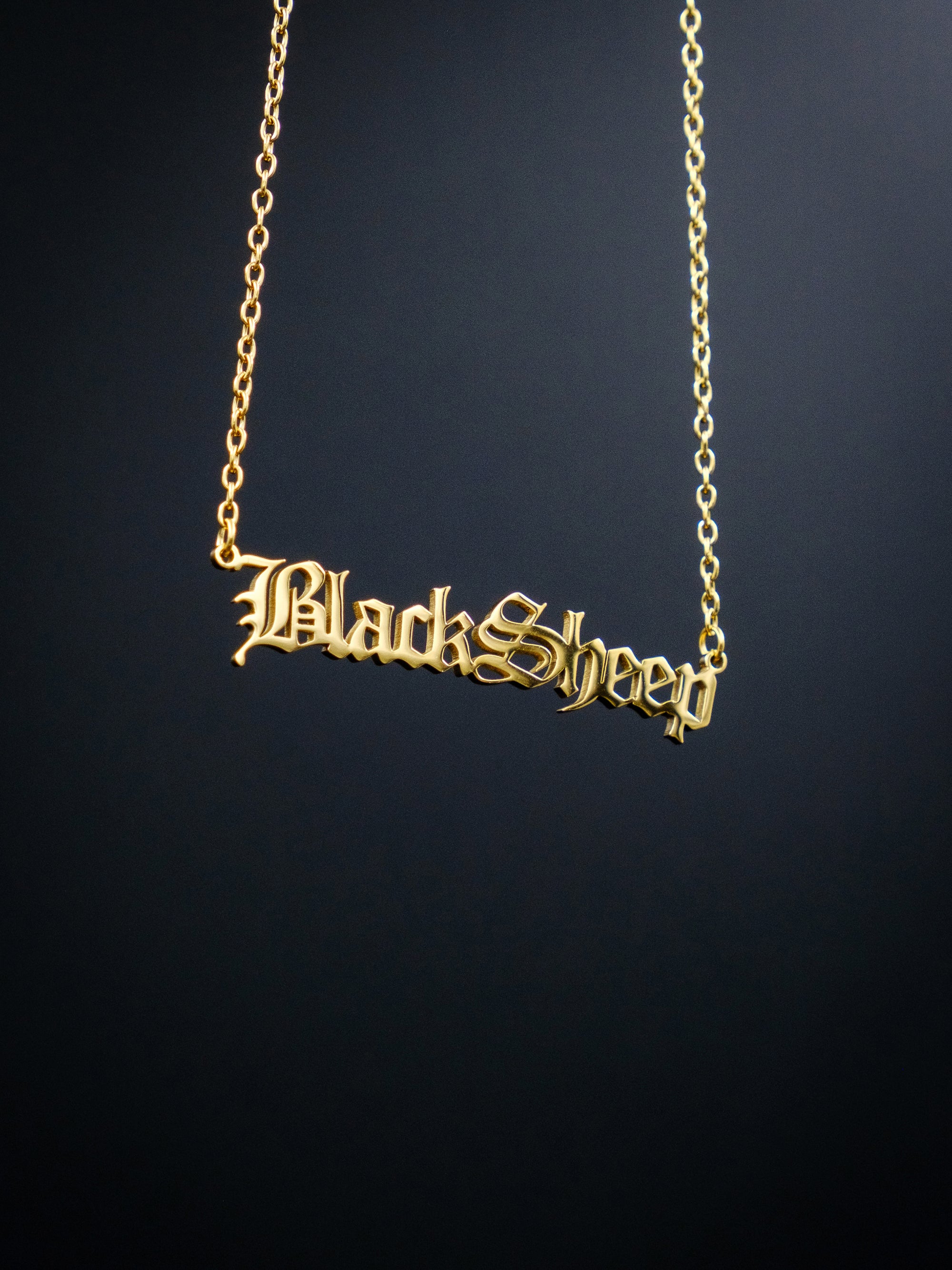 gold nameplate style necklace against a black background, reads BlackSheep in old english style font