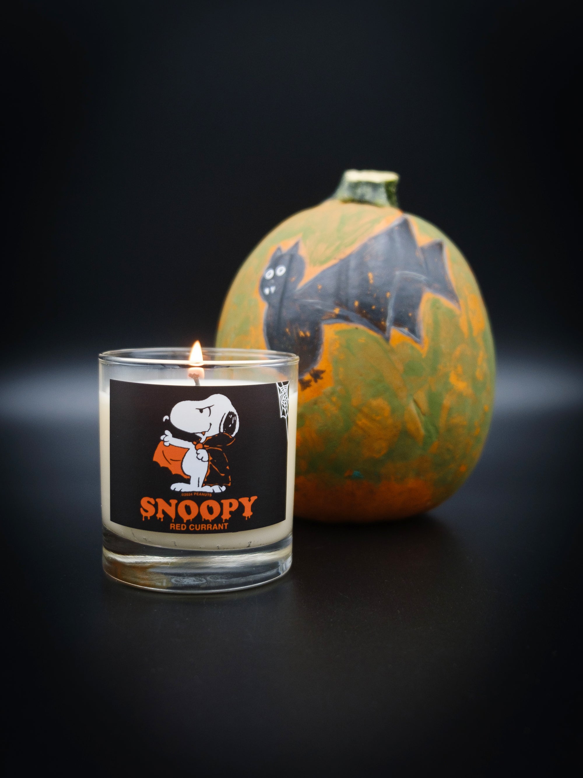 Lit votive Snoopy Candle with decorated pumpkin. This candle features a drippy halloween themed Snoopy text with vampire Snoopy graphic. 