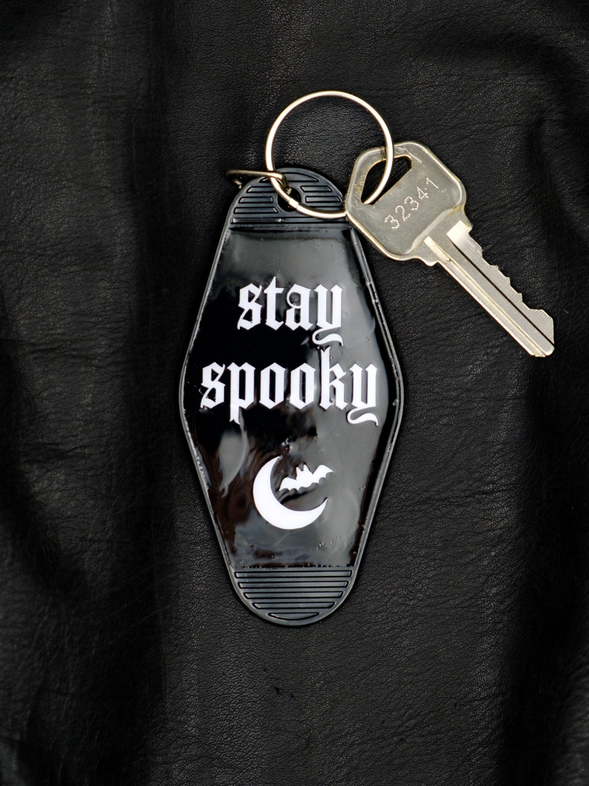 Black motel style keychain reads stay spooky in white with crescent moon and bat graphic