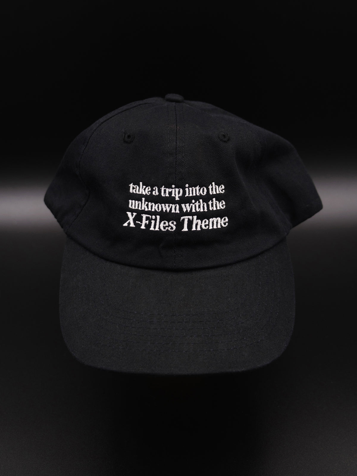 black hat with white embroidered text reads &quot;take a trip into the unknown with the X-Files theme&quot;