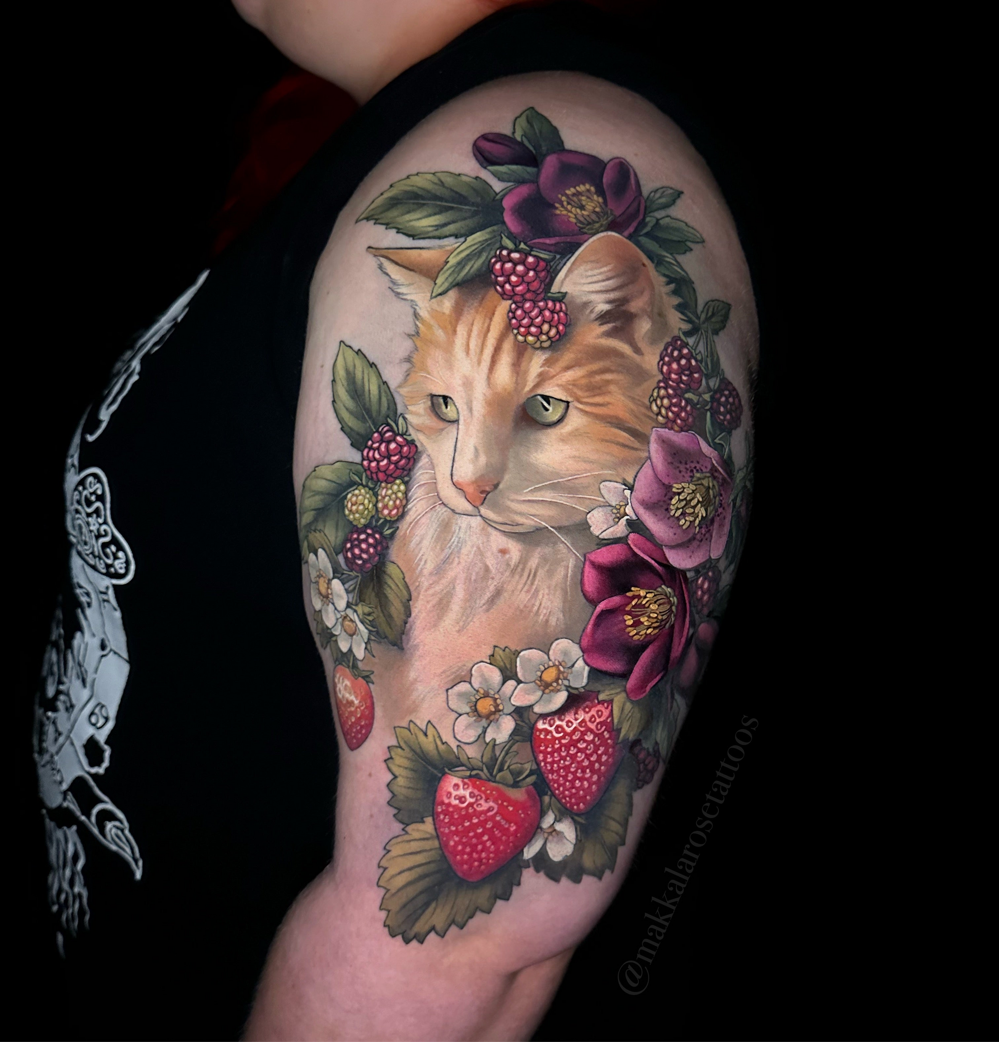 Cat upper arm tattoo with florals and berries