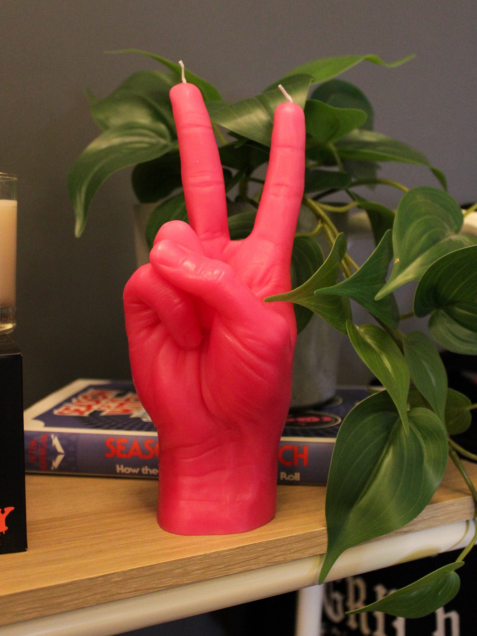 Hot pink hand shaped candle in a peace sign or victory pose. Candle features hyper detailed texture and two wicks. 