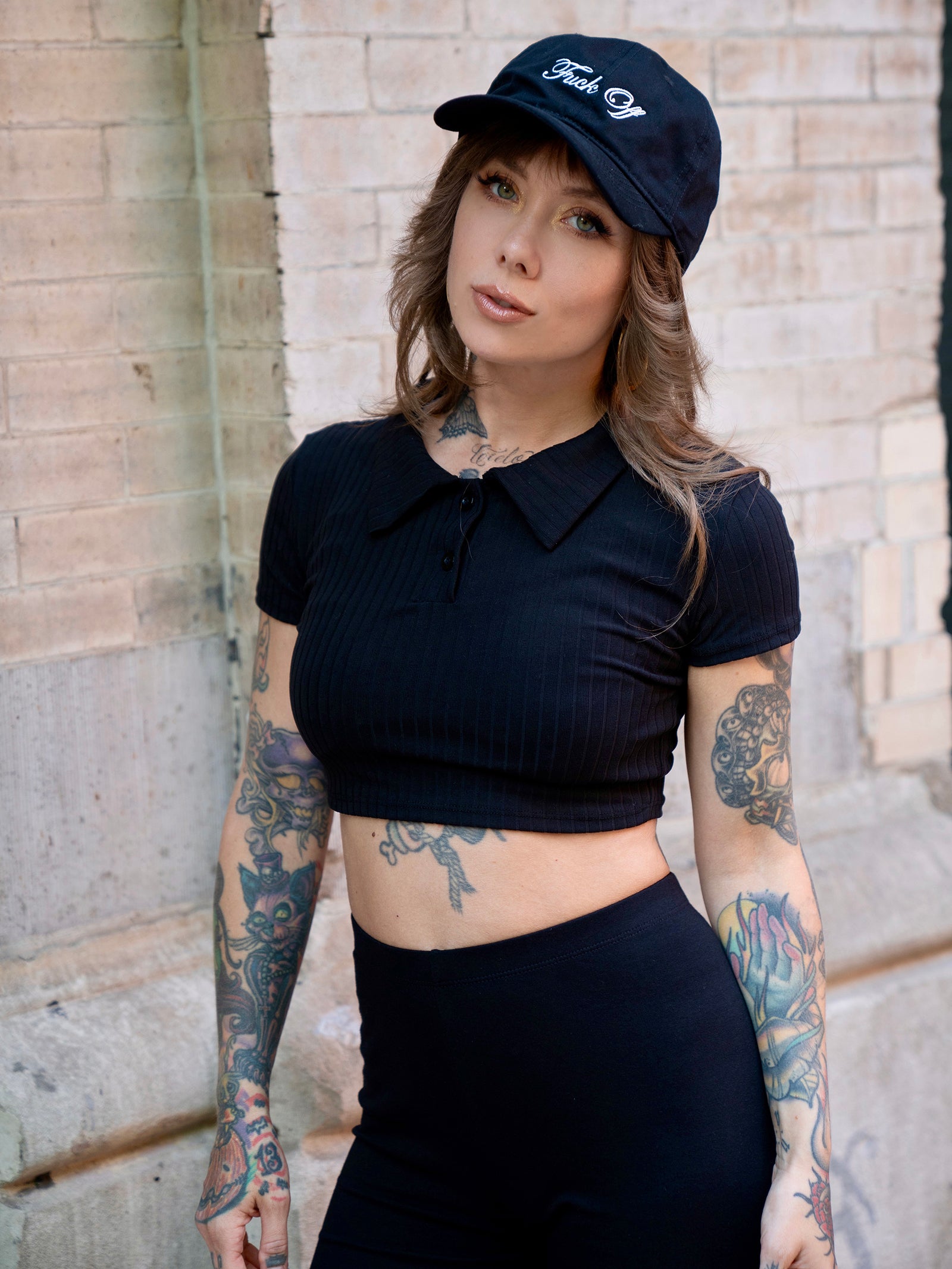 Megan Massacre wearing a crop black tee with the black and white Fuck Off embroidered dad style hat. 