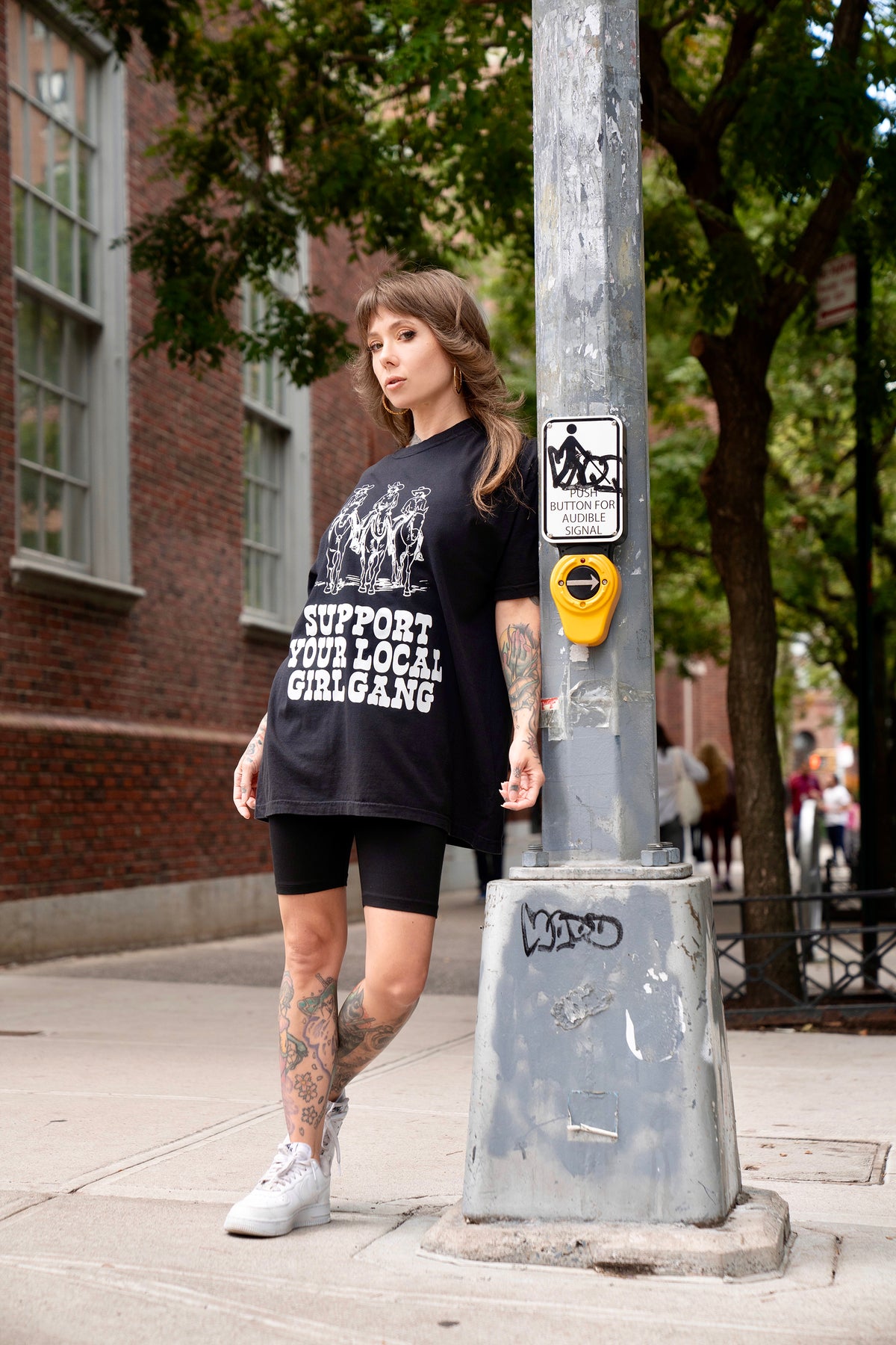 Megan Massacre wearing a western rock n roll aesthetic Support Your Local Girl Gang unisex t-shirt and black bike shorts. Casual, alternative, oversized style.