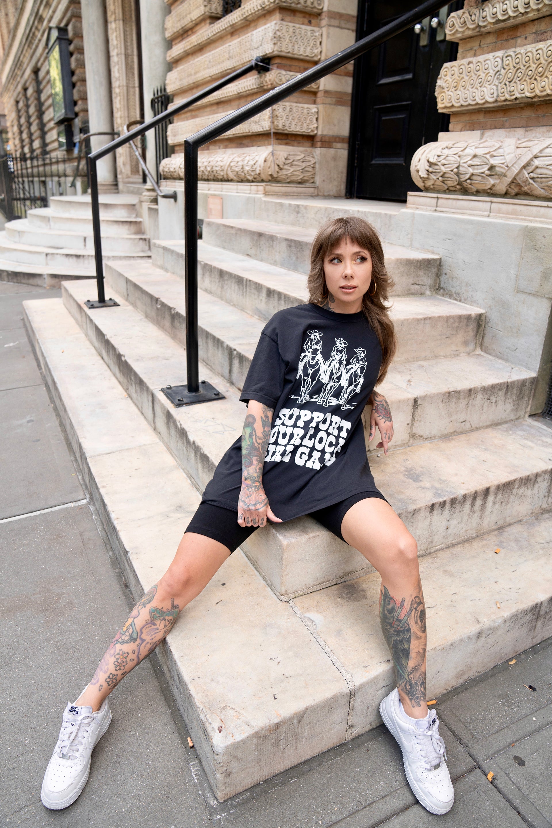 Megan Massacre wearing a western rock n roll aesthetic Support Your Local Girl Gang unisex t-shirt and black bike shorts. Casual, alternative, oversized style.