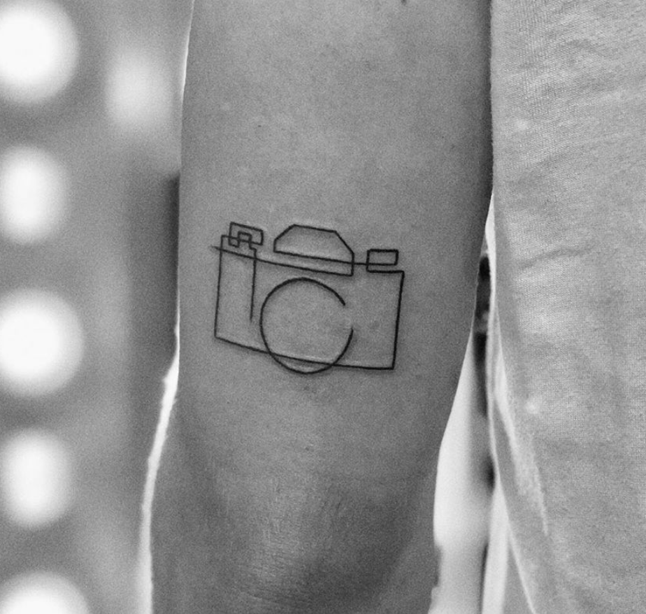 Tiny minimalistic camera tattooed on the finger.