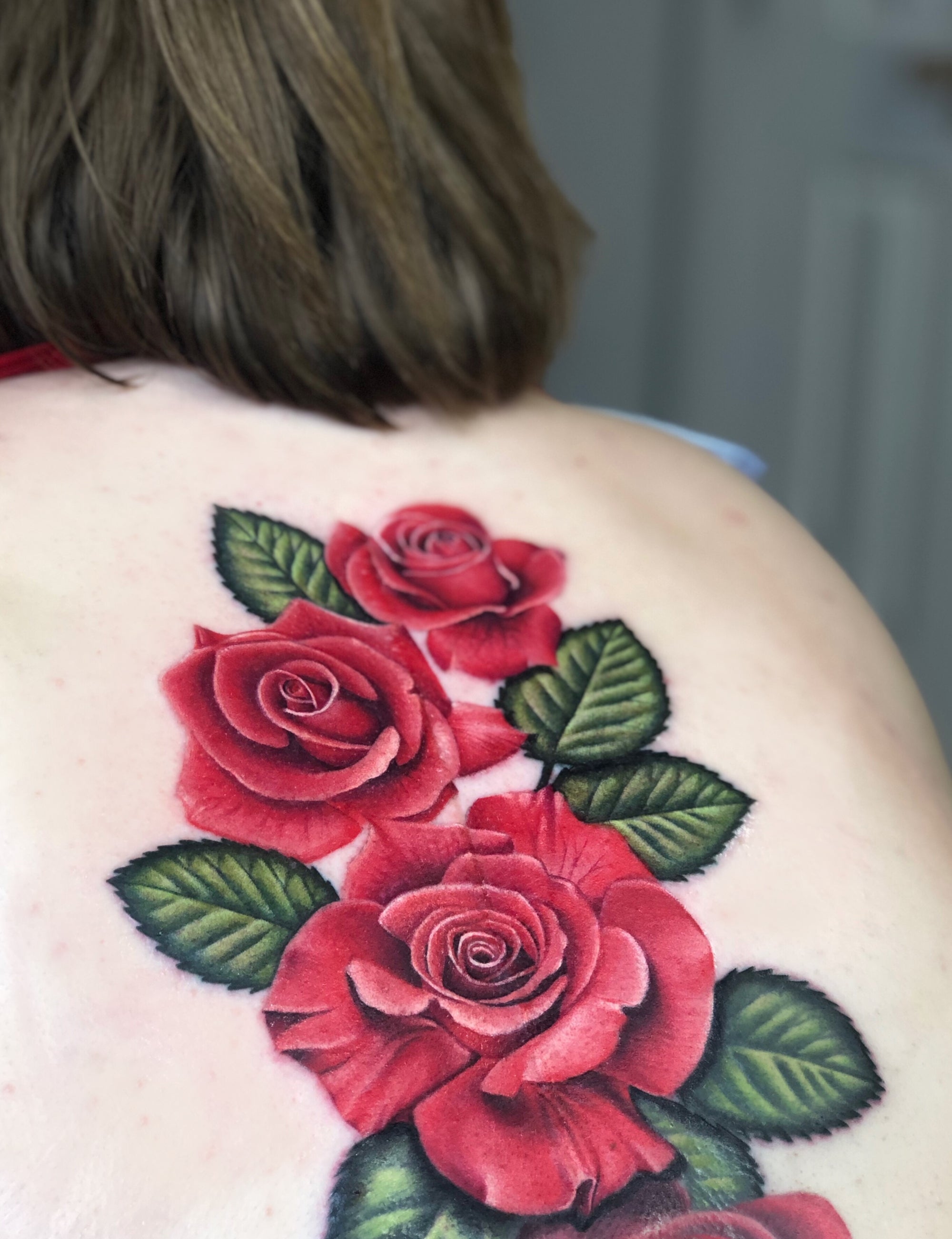 Color realism red roses with leaves back tattoo made by Megan Massacre. 