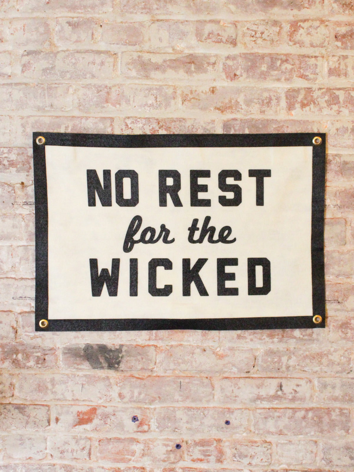 off white and black banner reads &quot;No Rest for the Wicked&quot; with gold grommets