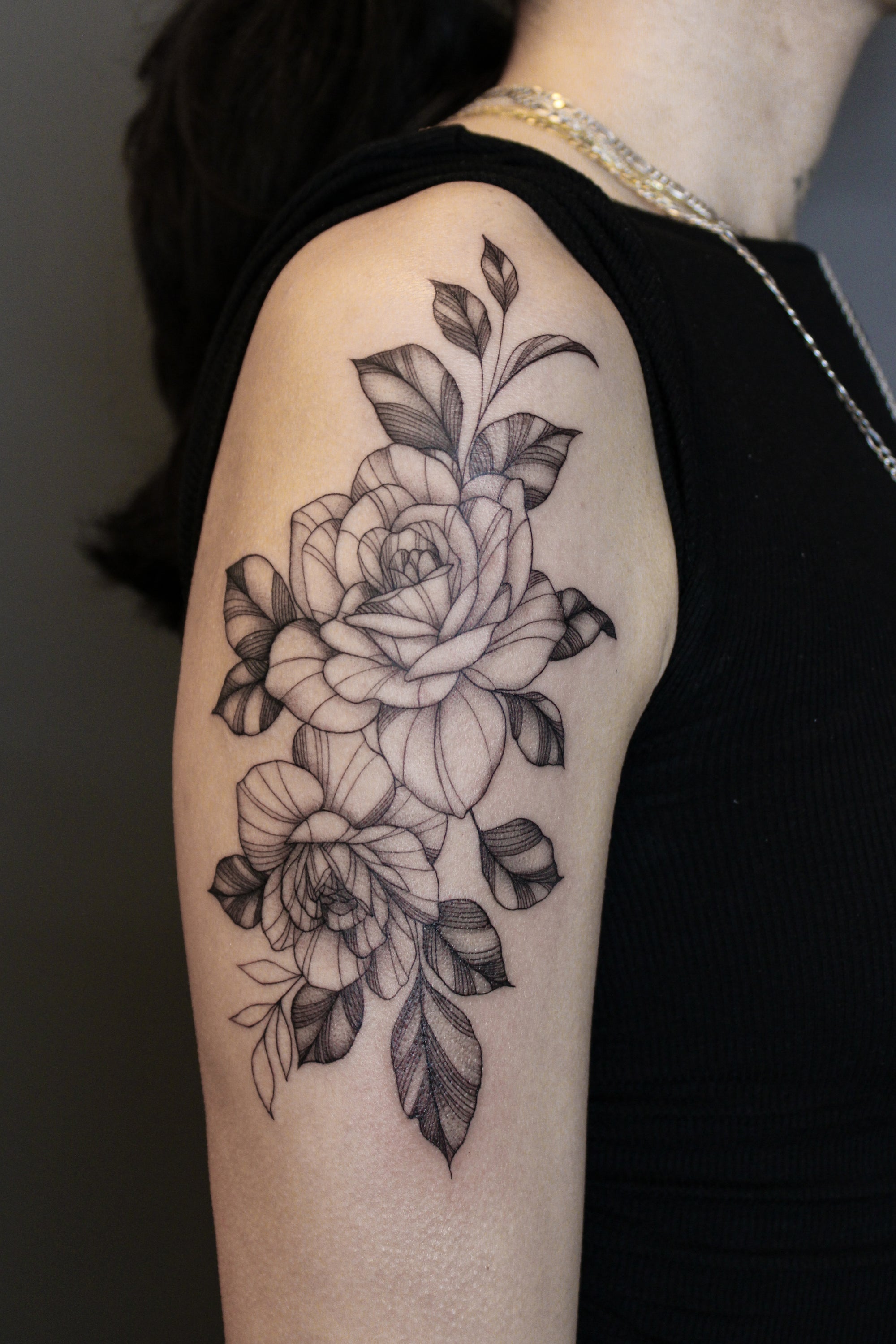 Fineline blackwork floral upper arm tattoo by Janice Danger. Two roses with light whip shading. 